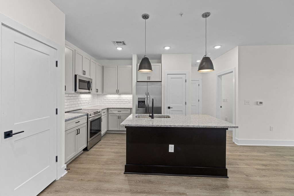 a renovated kitchen with white cabinets and a marble counter top