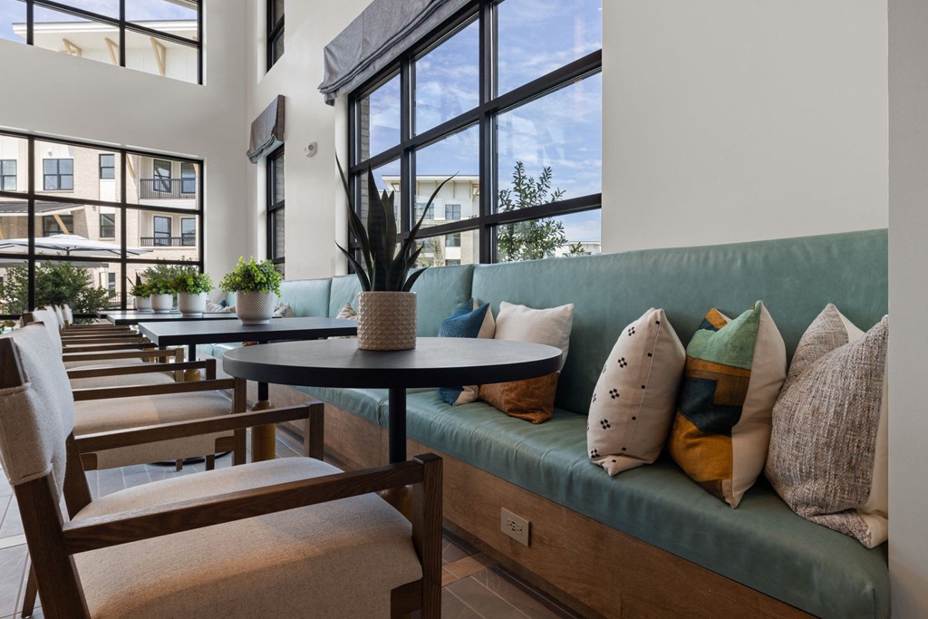 A restaurant with a long table and chairs with a view of the outside.