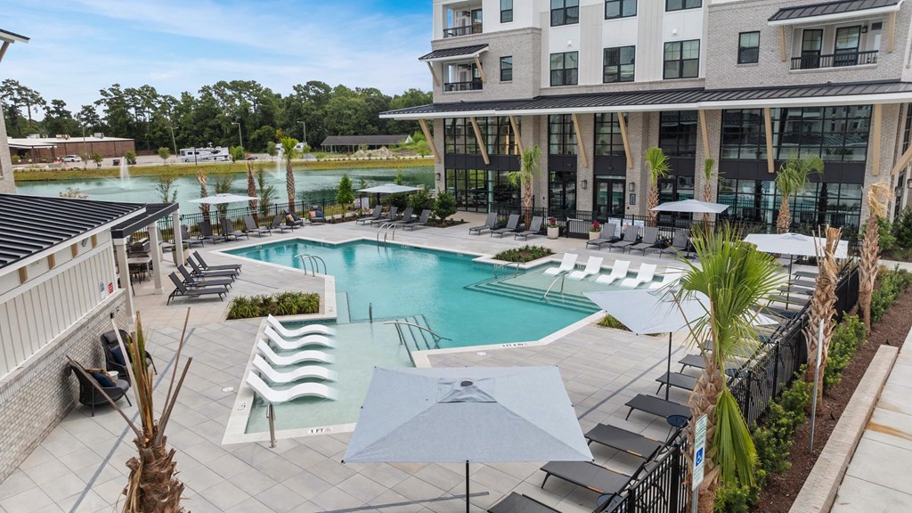 a large pool with chairs and umbrellas in front of a building