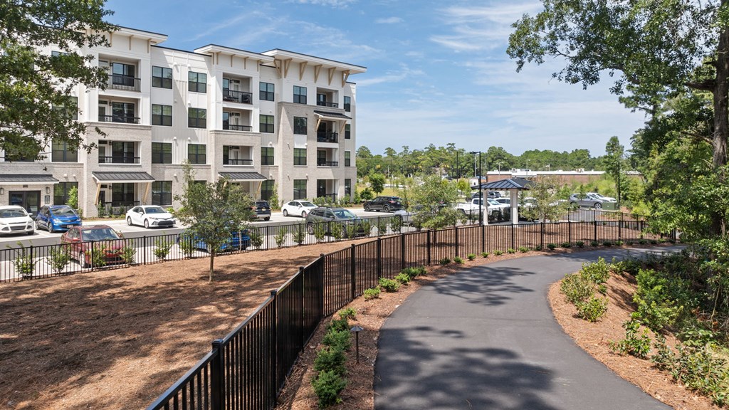 a pathway leading to an apartment building with a parking lot