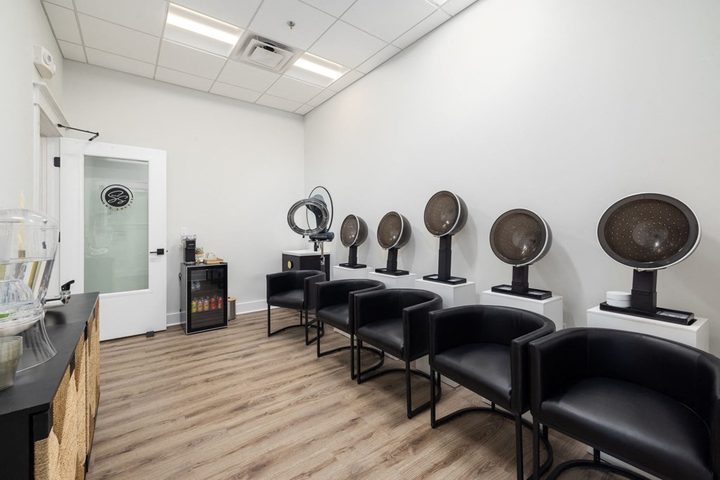 a room with chairs and a row of dryers in a white room