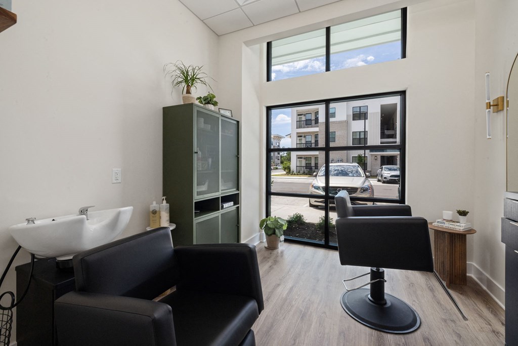 a living room with black chairs and a sink and a window
