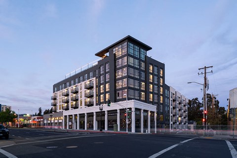A modern building with a black and white facade is illuminated by the setting sun.