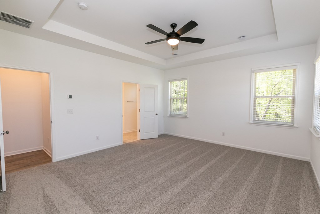 a bedroom with white walls and a ceiling fan