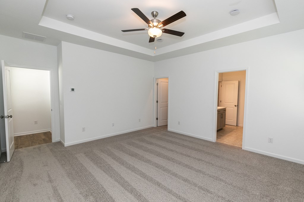 a bedroom with white walls and a ceiling fan