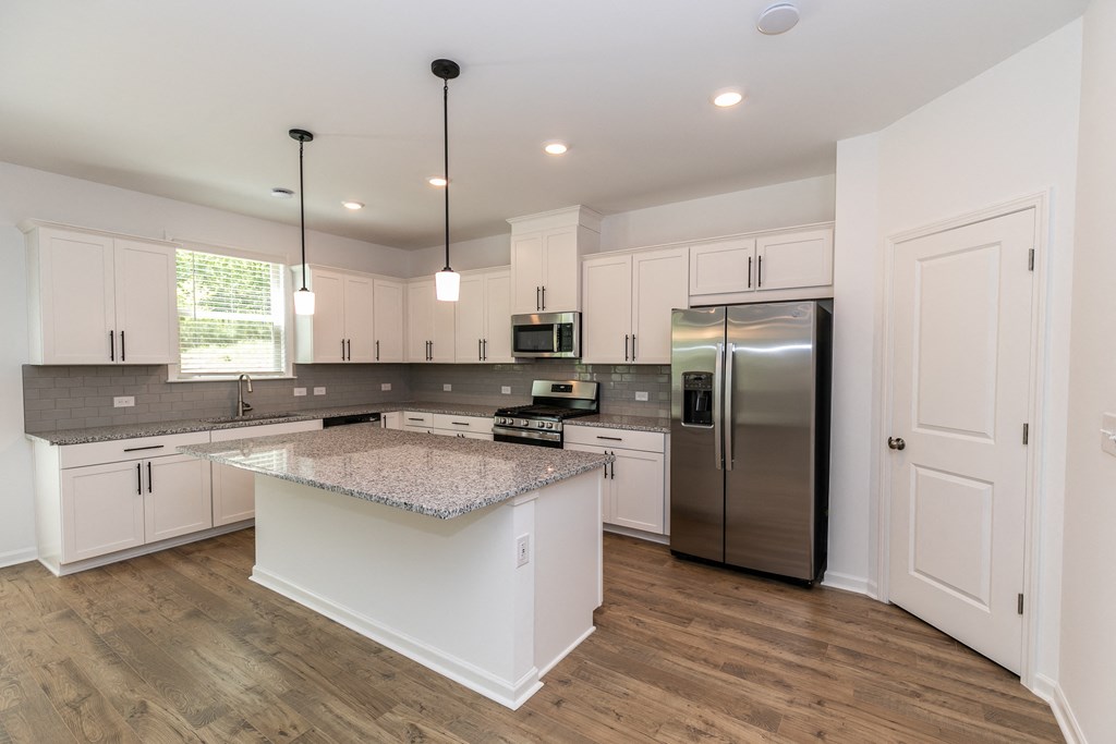 a kitchen with white cabinets and a large island with granite countertops