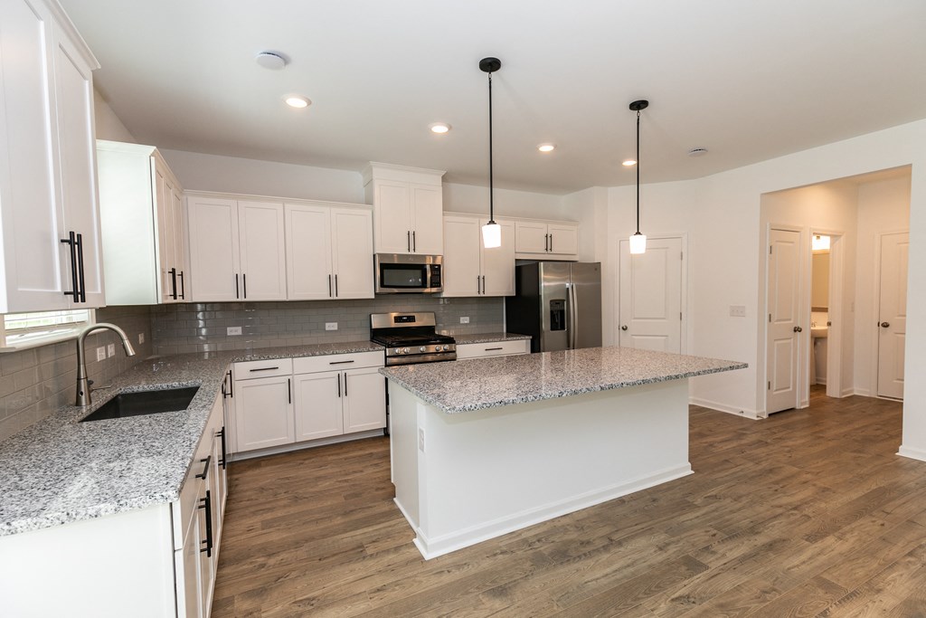 a kitchen with white cabinets and a white island with granite countertops