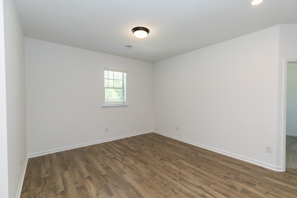 a bedroom with white walls and hardwood floors