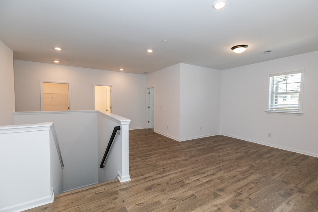 a bedroom with hardwood floors and white walls