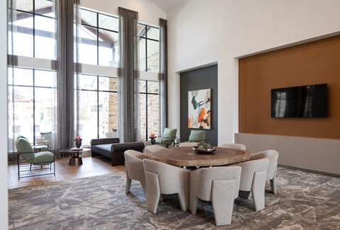 a living room with large windows and a large round table with chairs