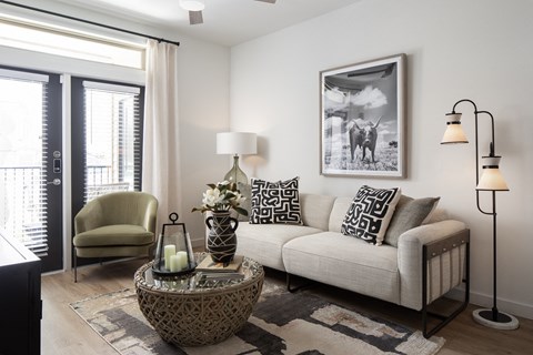 A living room with a sofa, chair, and a table with a vase and candles on it.