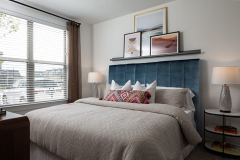 a bedroom with a large window and a large bed with a blue headboard