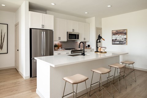 A kitchen with a white counter and bar stools.