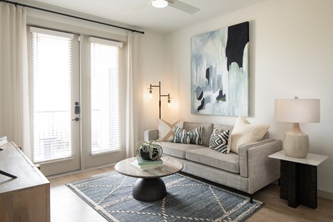 A living room with a grey couch, a coffee table, and a painting on the wall.