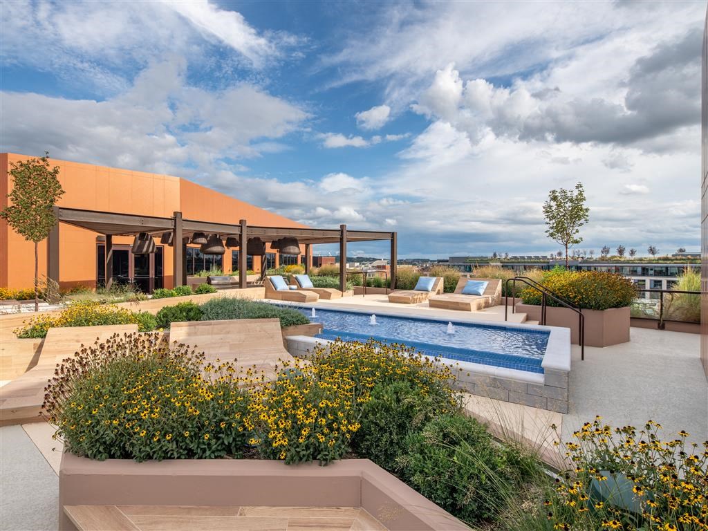 a rooftop pool with lounge chairs and a building in the background