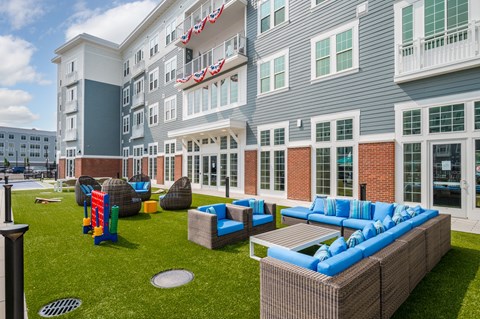 an outdoor lounge area with couches and chairs in front of a building