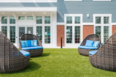 a group of outdoor chairs with blue pillows in front of a building