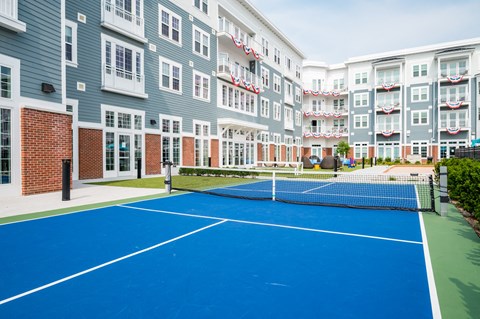 a blue tennis court in front of an apartment building