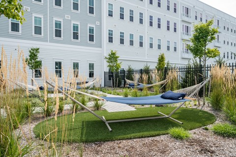a courtyard with hammocks and grass in front of a white building