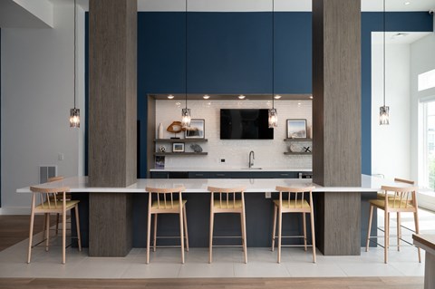 a kitchen with a large island with wooden chairs and a mirror