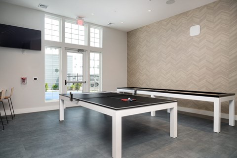 a games room with two ping pong tables and a tv