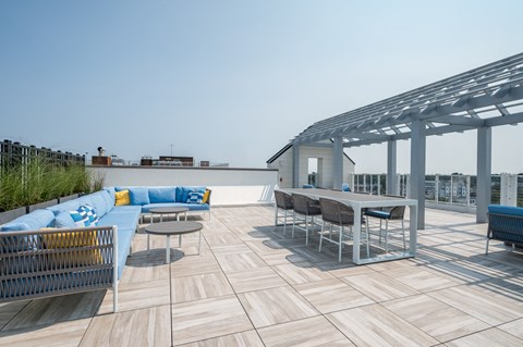 a roof top patio with tables and chairs and a blue couch