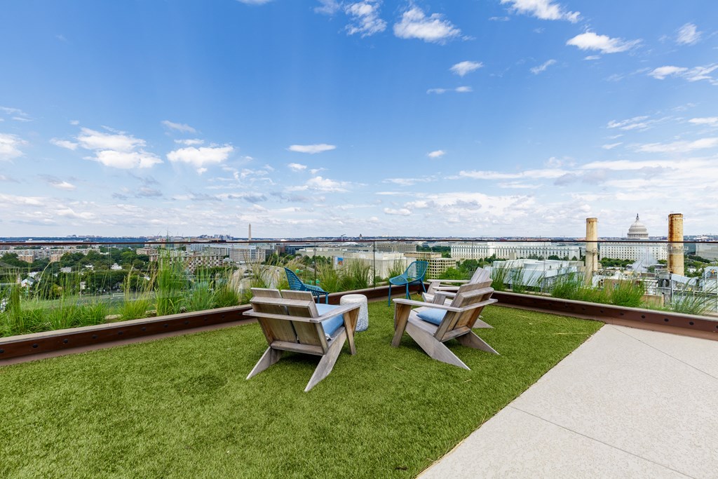 Two chairs are on a lawn with a city view in the background.