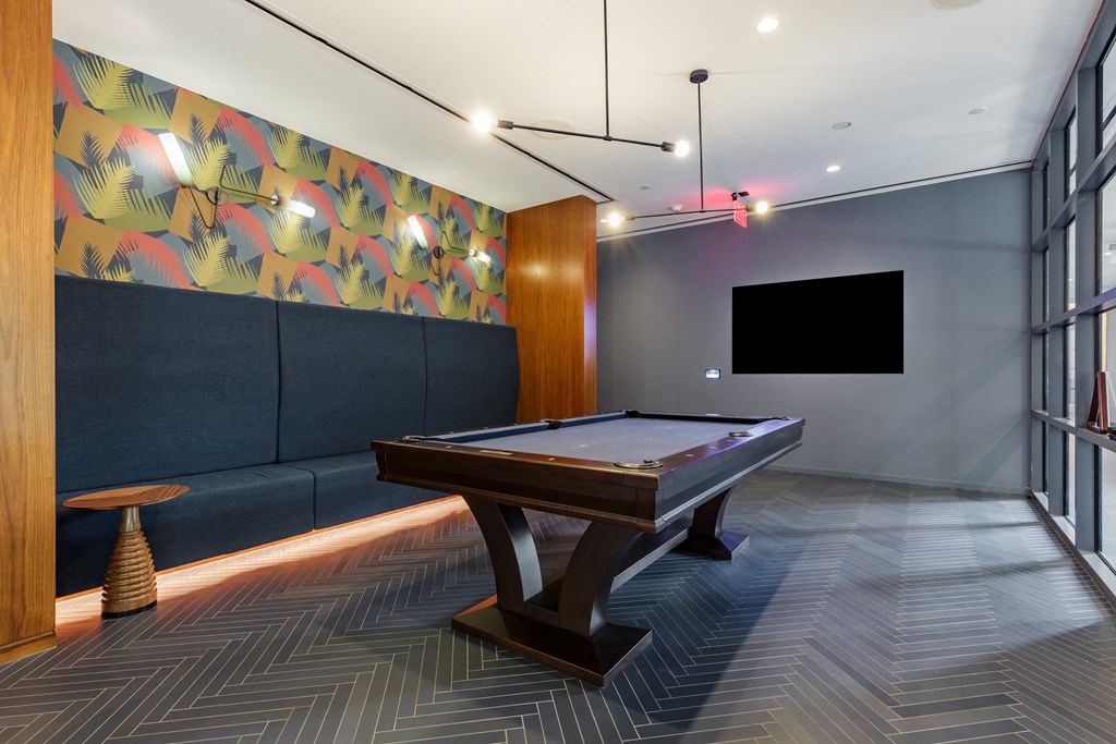 A pool table in a room with a blue couch and a TV.