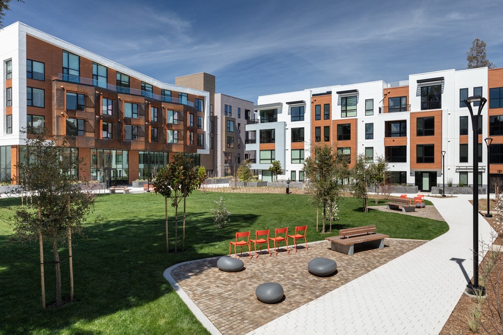 a courtyard with trees and benches in front of a building