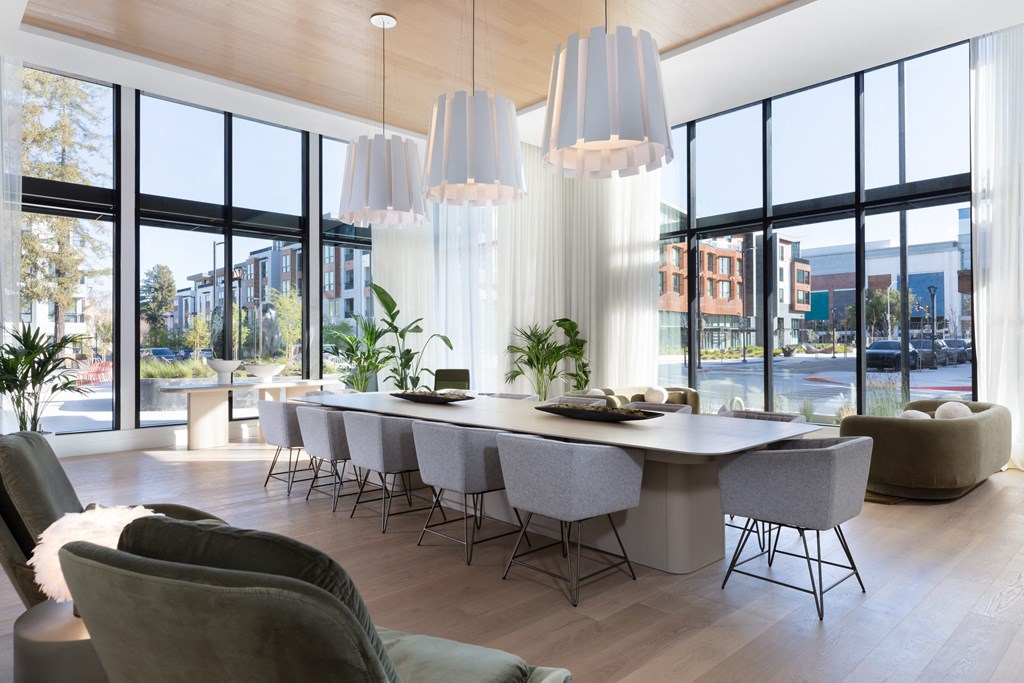 a long dining table with chairs in front of a wall of windows
