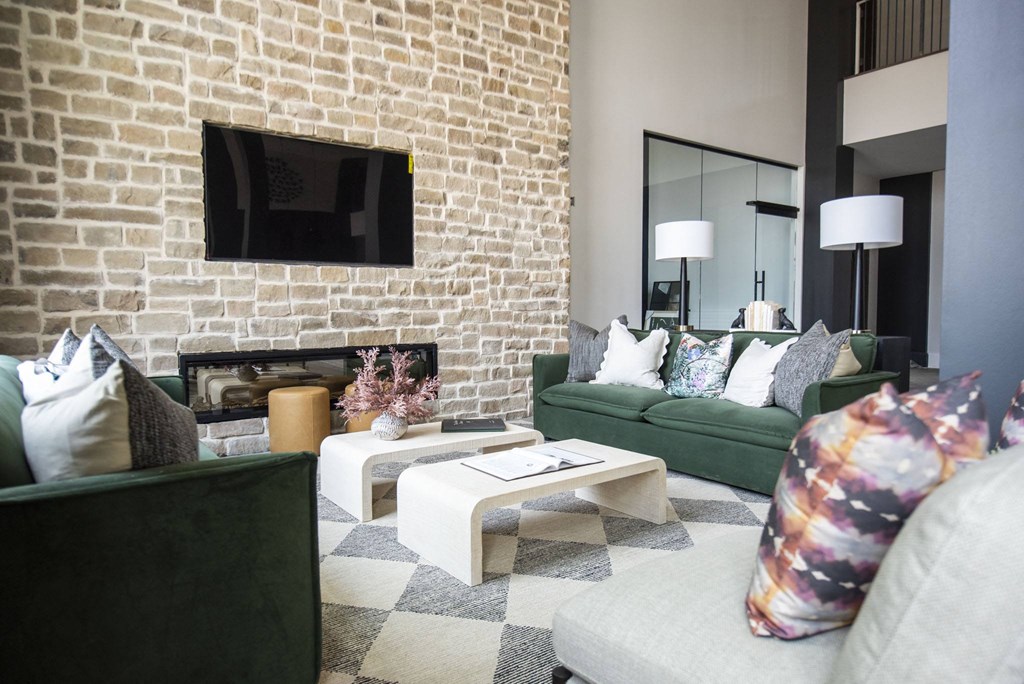 a living room with green couches and a brick wall