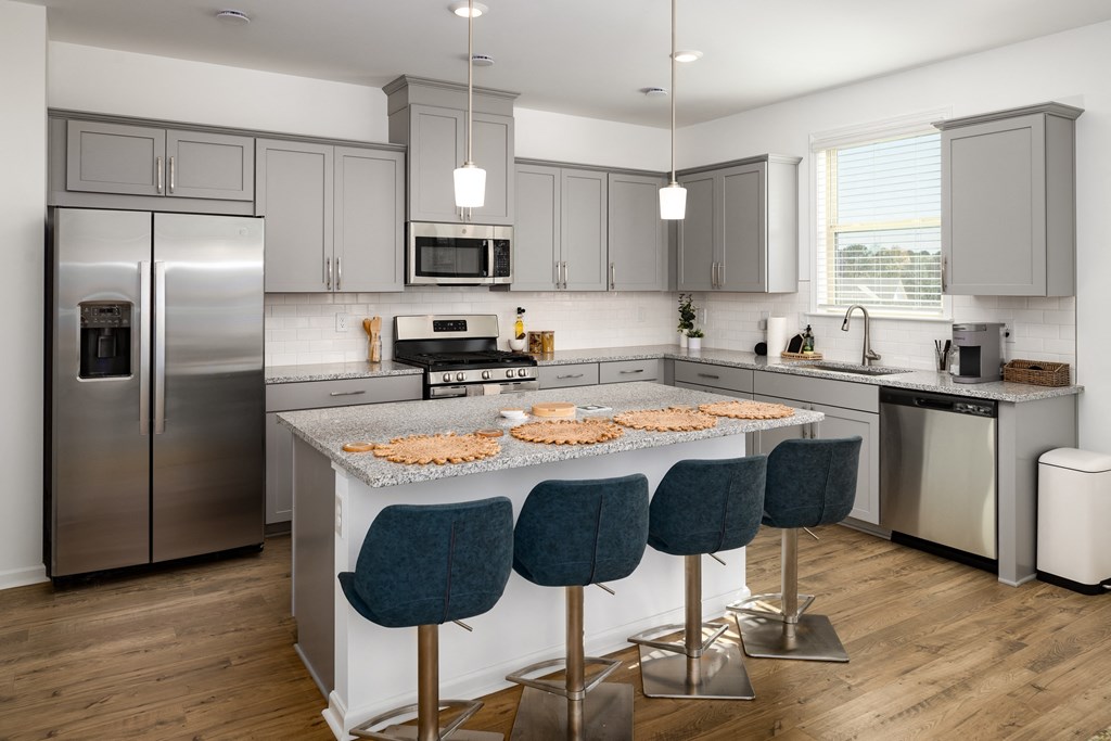 a kitchen with stainless steel appliances and an island with blue chairs