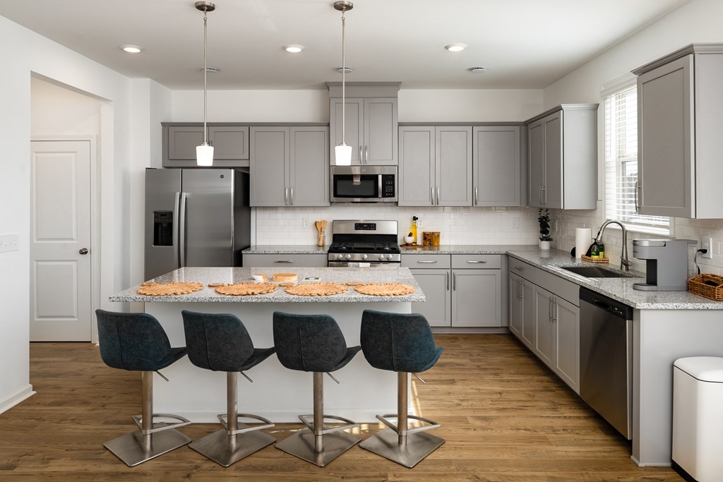 a kitchen with gray cabinets and a white island with chairs
