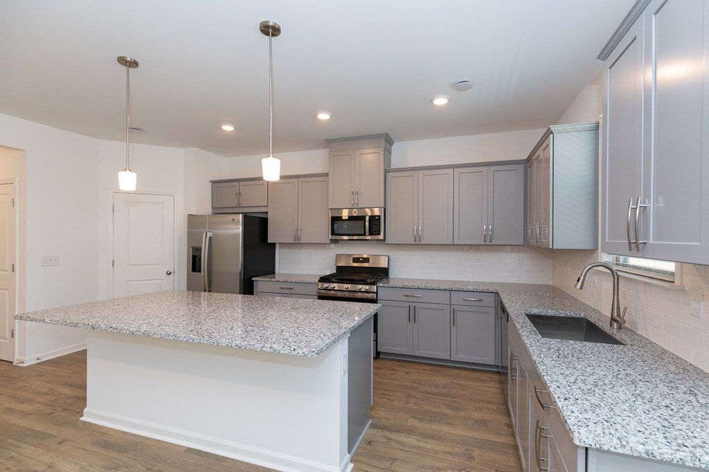 a kitchen with gray cabinets and white countertops