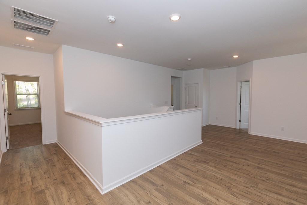 a large living room with white walls and hardwood floors