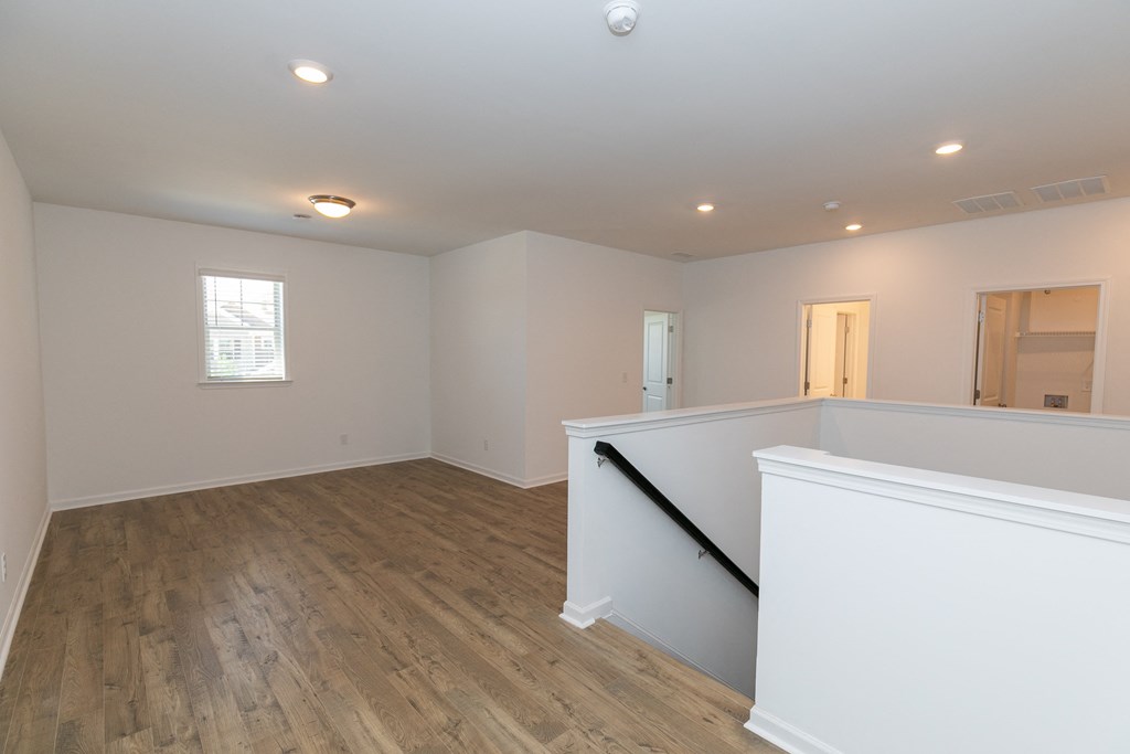 a large living room with hardwood floors and white walls