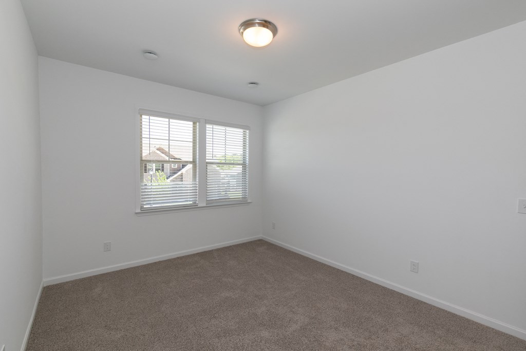 a bedroom with white walls and a large window