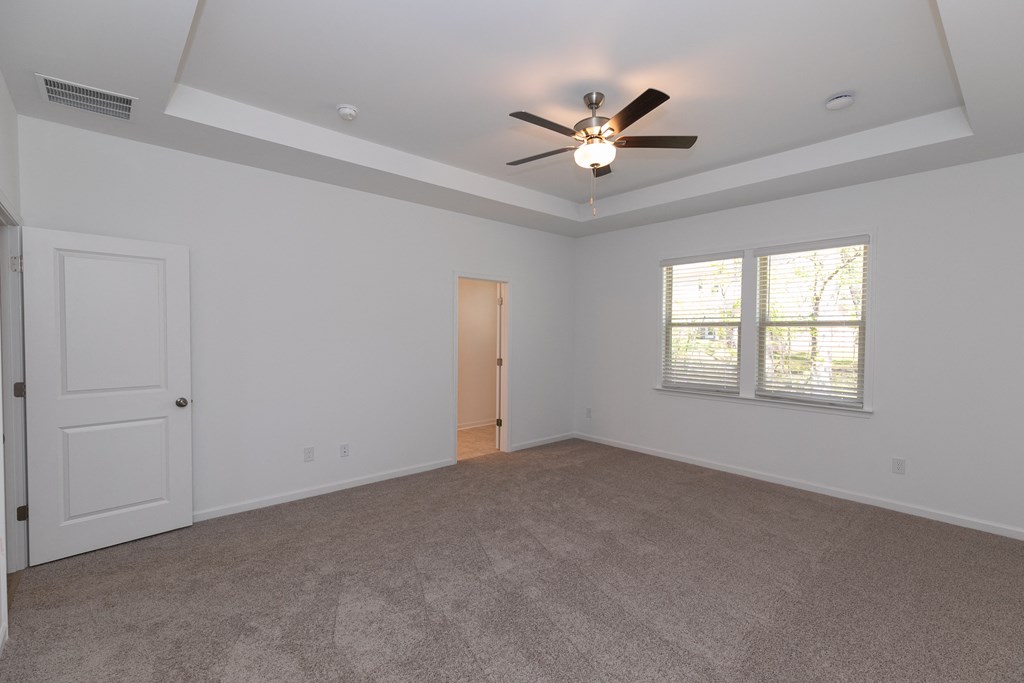 an empty bedroom with a ceiling fan