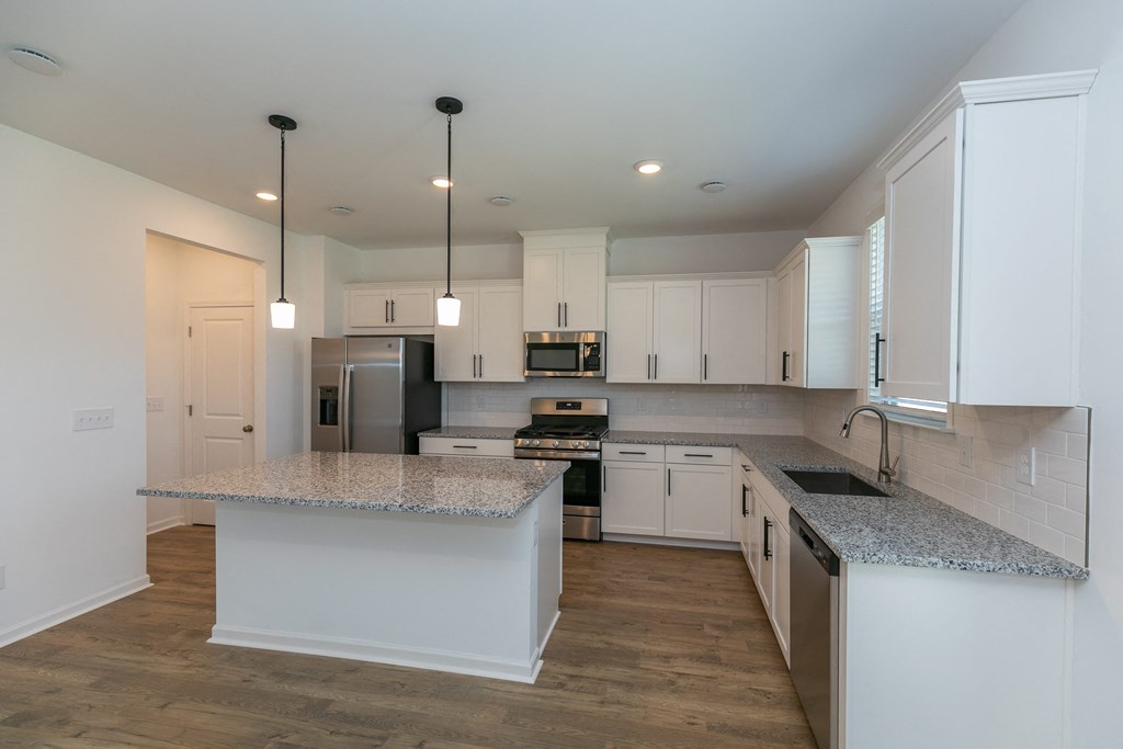 a kitchen with white cabinets and an island with granite countertops