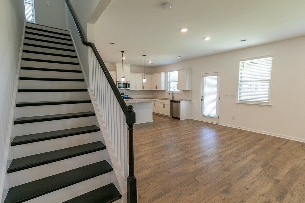a living room and kitchen in a house with hardwood floors and white walls