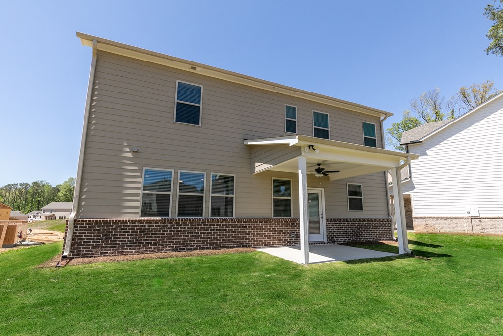 the back of a house with a green lawn and a blue sky