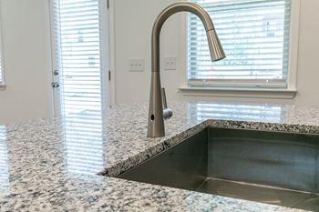 a kitchen sink with a faucet in front of a window with blinds