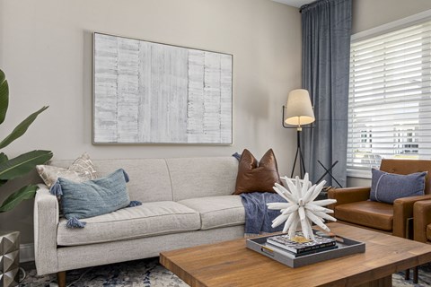 A living room with a grey couch, a coffee table, and a large abstract painting on the wall.