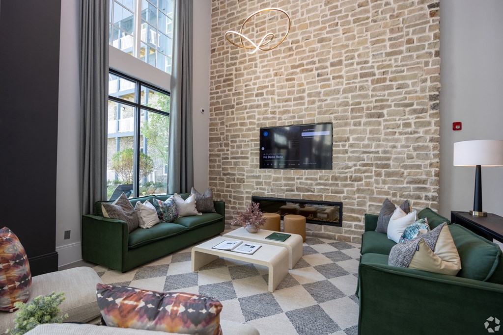 Clubroom with green couches and a brick wall and a television