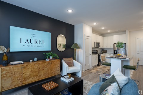 a living room with a tv on the wall and a kitchen