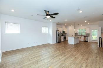 a kitchen and living room with hardwood floors and a ceiling fan