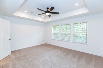 a bedroom with a ceiling fan and three windows