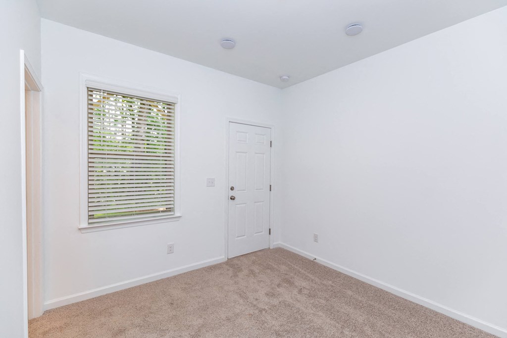 a bedroom with white walls and carpet