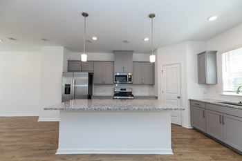 a kitchen with gray cabinets and a white island with granite countertops