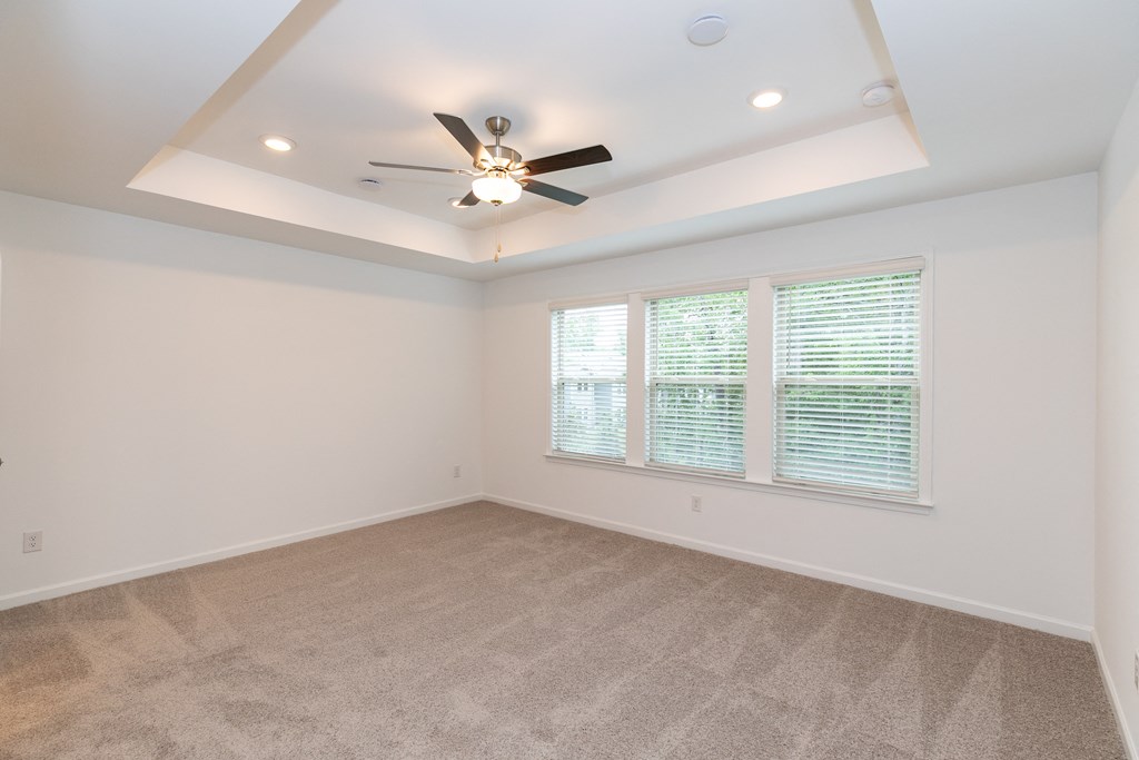 a bedroom with a ceiling fan and three windows
